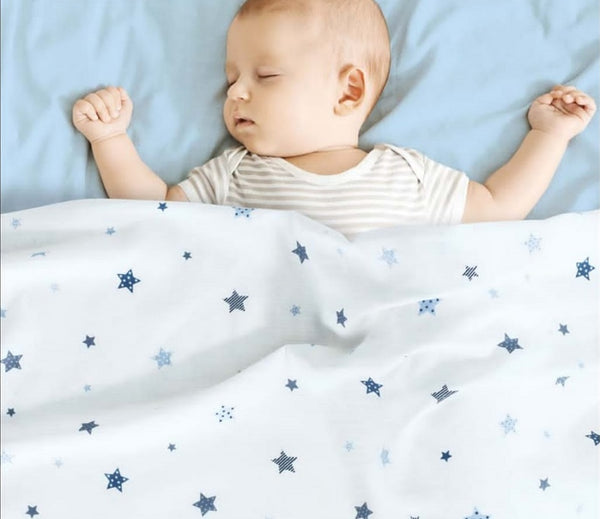 A peaceful sleeping baby tucked under a white patterned textile suitable for custom poplin fabric