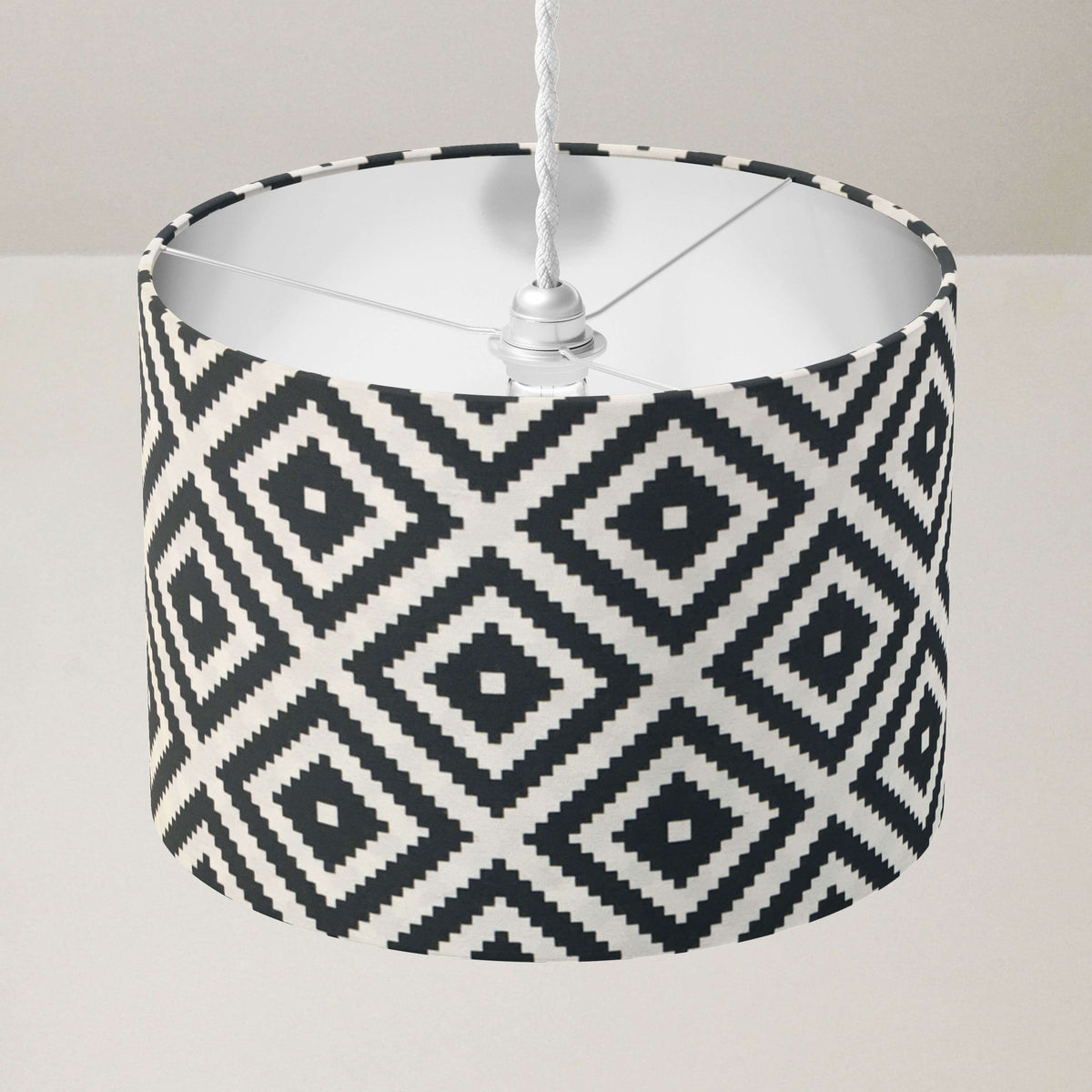 Ceiling drum lampshade with black and white geometric pattern on a plain background.
