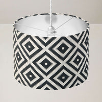 Ceiling drum lampshade with black and white geometric pattern on a plain background.