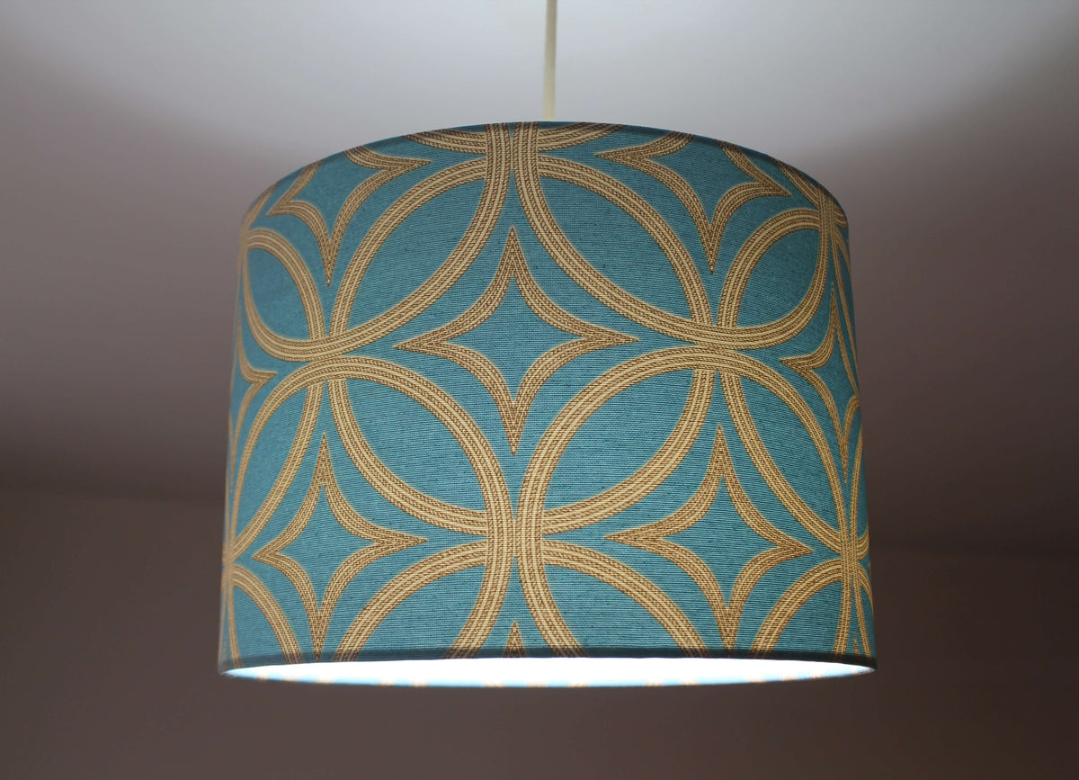 Teal blue ceiling lampshade with gold geometric pattern hanging on a ceiling.