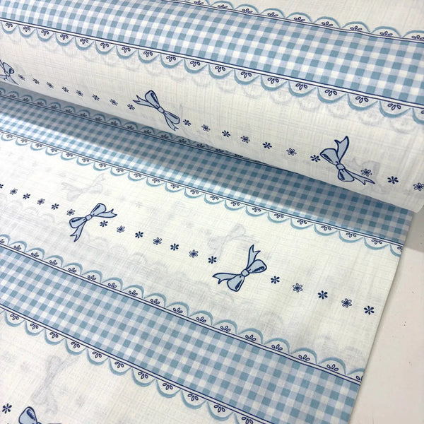 Blue gingham bow cotton poplin fabric featuring striped bands, ribbon bows and lace-effect borders on a white background.