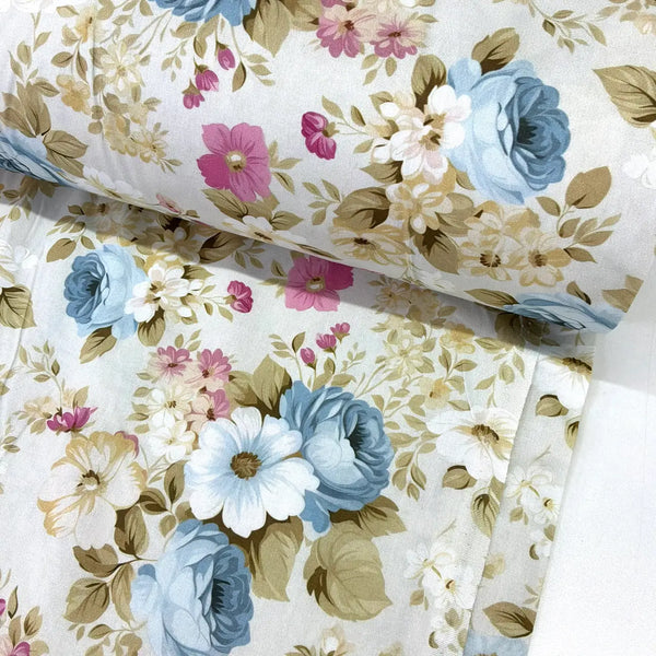Blue roses cotton poplin fabric featuring vintage floral blooms in blue, cream and pink with green foliage on a white background.