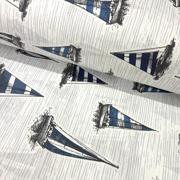 Blue and white nautical fabric featuring hand-drawn sailboats with striped sails on a textured light background.