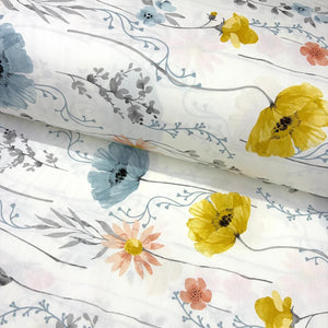 A white cotton poplin fabric with a watercolour floral print featuring yellow poppies, blue flowers, peach blossoms, and gray leaves on delicate stems.