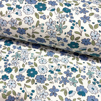 Floral fabric patterned with denim blue flowers and green leaves on a white background.