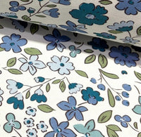 Floral upholstery & curtain fabric patterned with small blue flowers and green leaves on a white background.