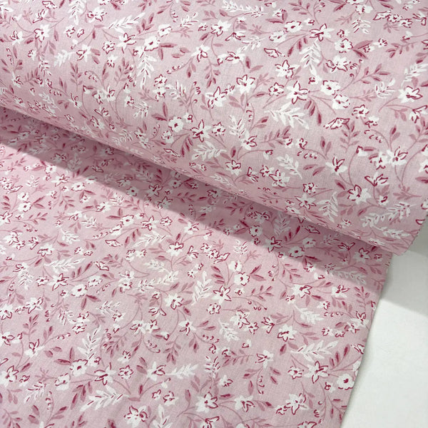 Ditsy floral patterned fabric with small white flowers on a blush pink background.