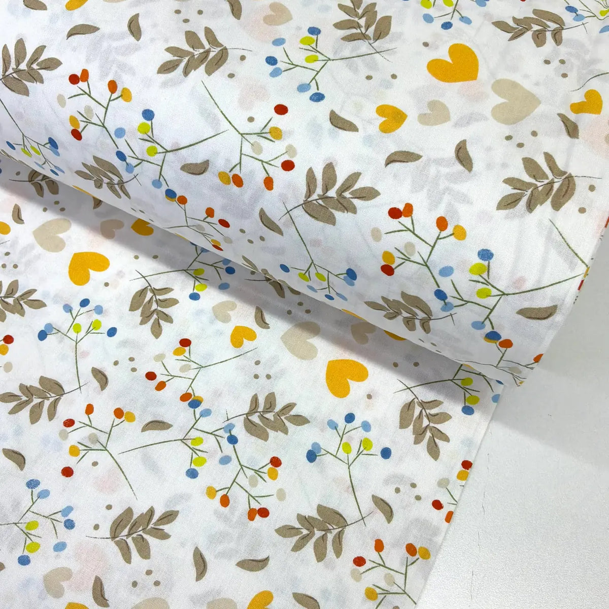 Botanical cotton poplin fabric featuring colourful yellow and cream hearts, blue, orange and green berry sprigs, taupe leaves on a white background.