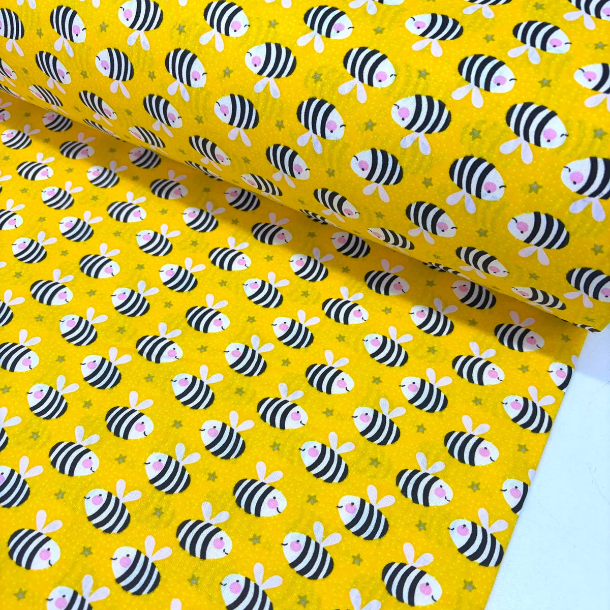 Bumble bee cotton fabric featuring black and white striped bees on a bright yellow background, ideal for quilting, children's sewing, nursery décor and craft projects.