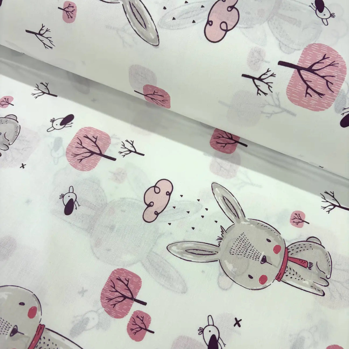 Children's cotton fabric with grey cartoon bunny and pink tree pattern on a white background.