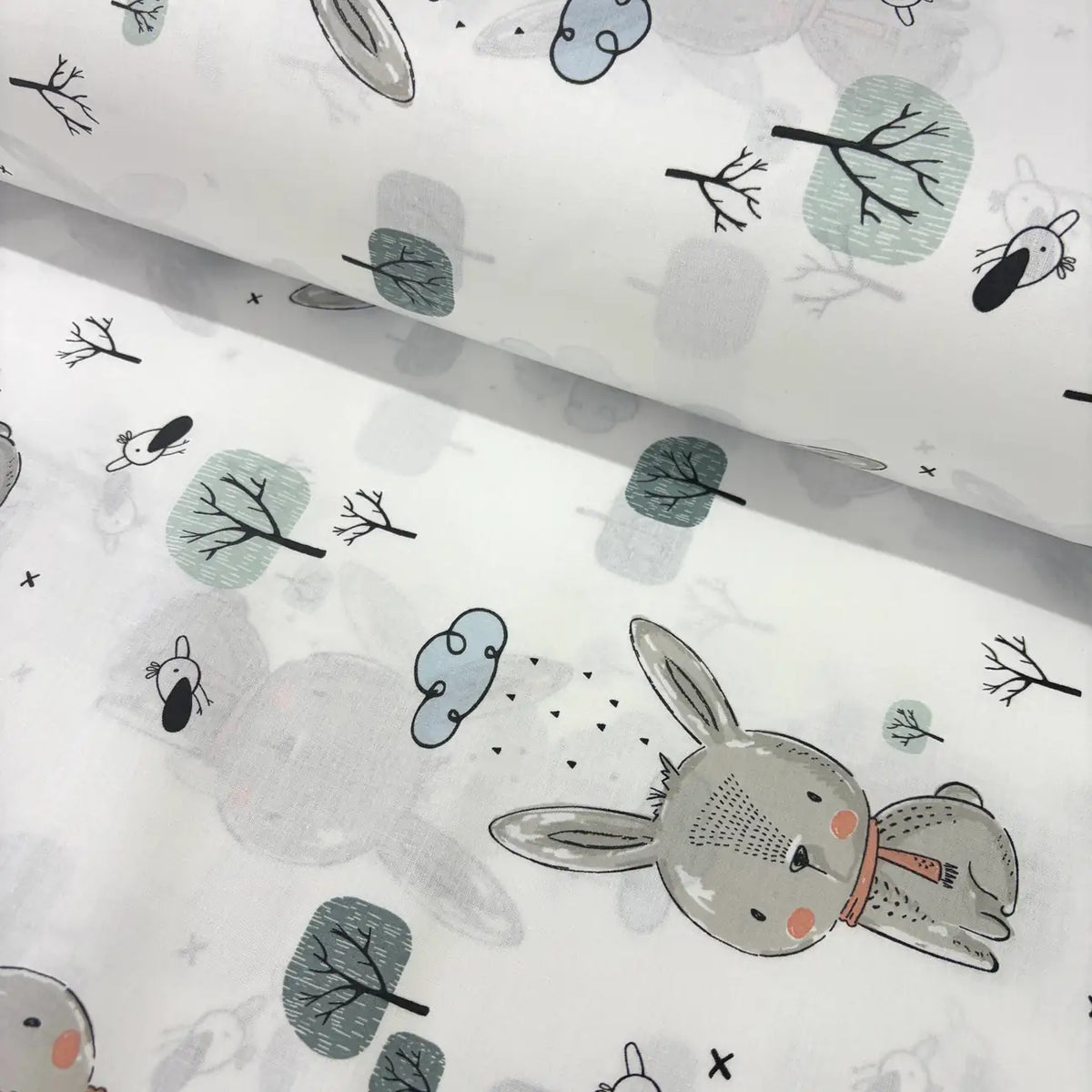 Fabric with bunny and tree pattern on a white background.