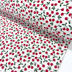 Retro vintage cotton poplin fabric featuring an all-over red cherry fruit print with green leaves on a white background. 