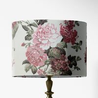 Vintage style pink floral patterned table and floor lampshade on a white background.