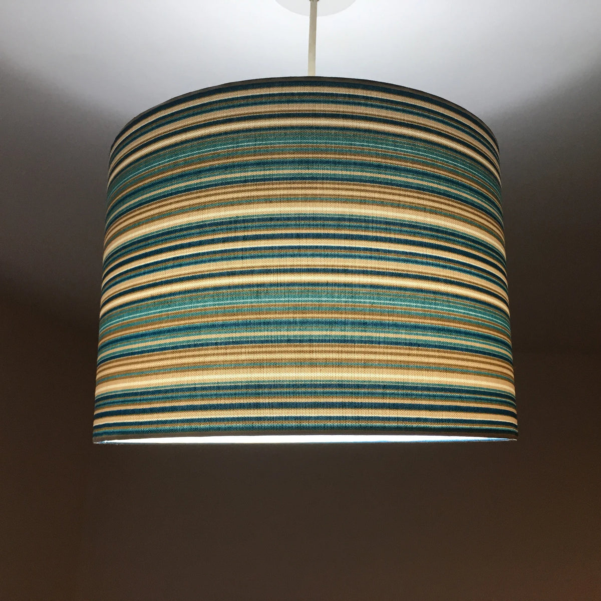 A teal blue and beige striped ceiling lampshade on a plain background.