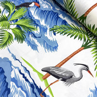 Tropical upholstery fabric with exotic birds, palm trees, and blue waves on a white background.