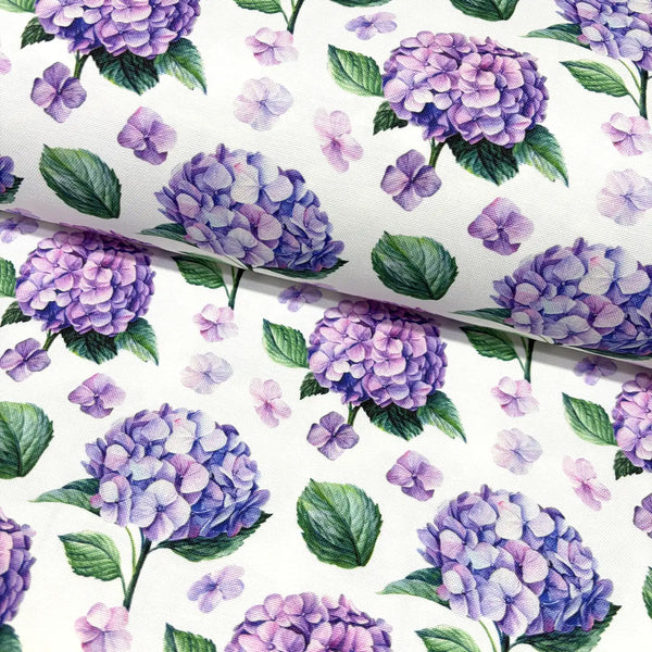 Upholstery & curtain fabric patterned with purple hydrangeas and green leaves on a white background.