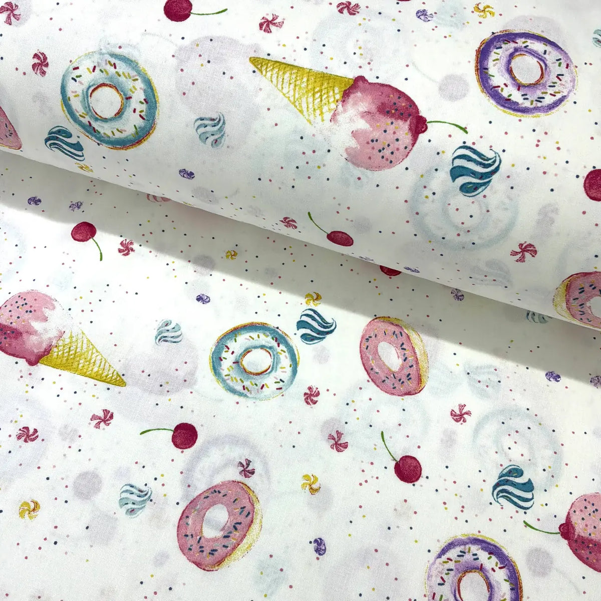 Patterned cotton poplin fabric with colorful donuts, ice cream cones, and cherries on a white background.