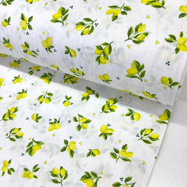 Mini lemon print cotton fabric featuring small yellow lemons and green leafy sprigs on a white background.
