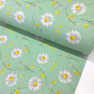 Mint green cotton poplin fabric featuring white daisy flowers, delicate wildflower sprigs and scattered yellow petals, ideal for dressmaking, quilting and crafts.