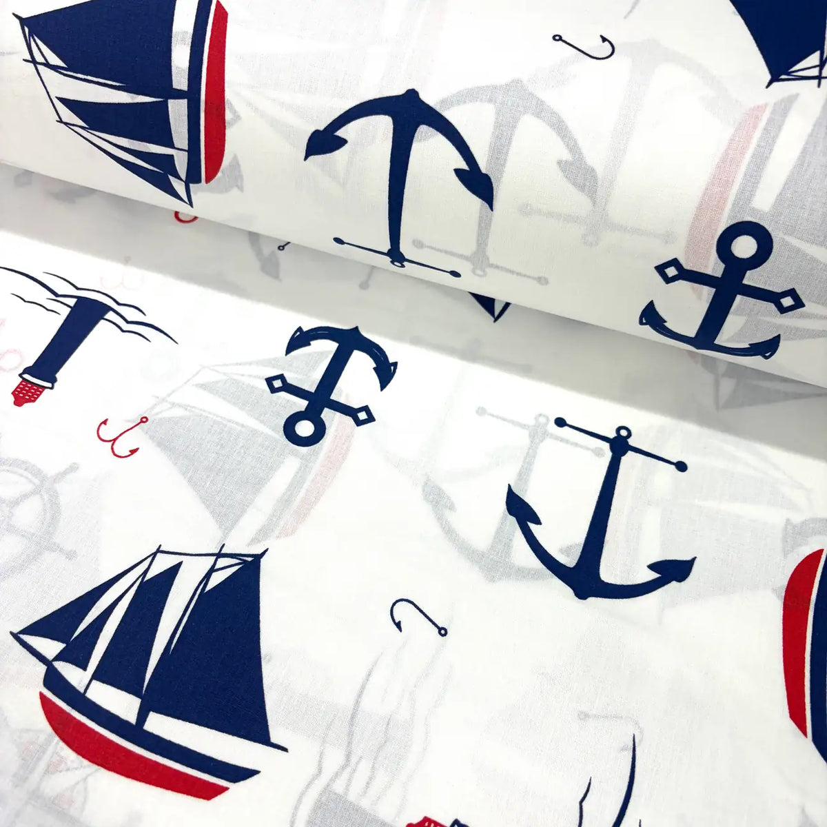 Cotton poplin fabric with nautical patterns including anchors and sailboats on a white background.