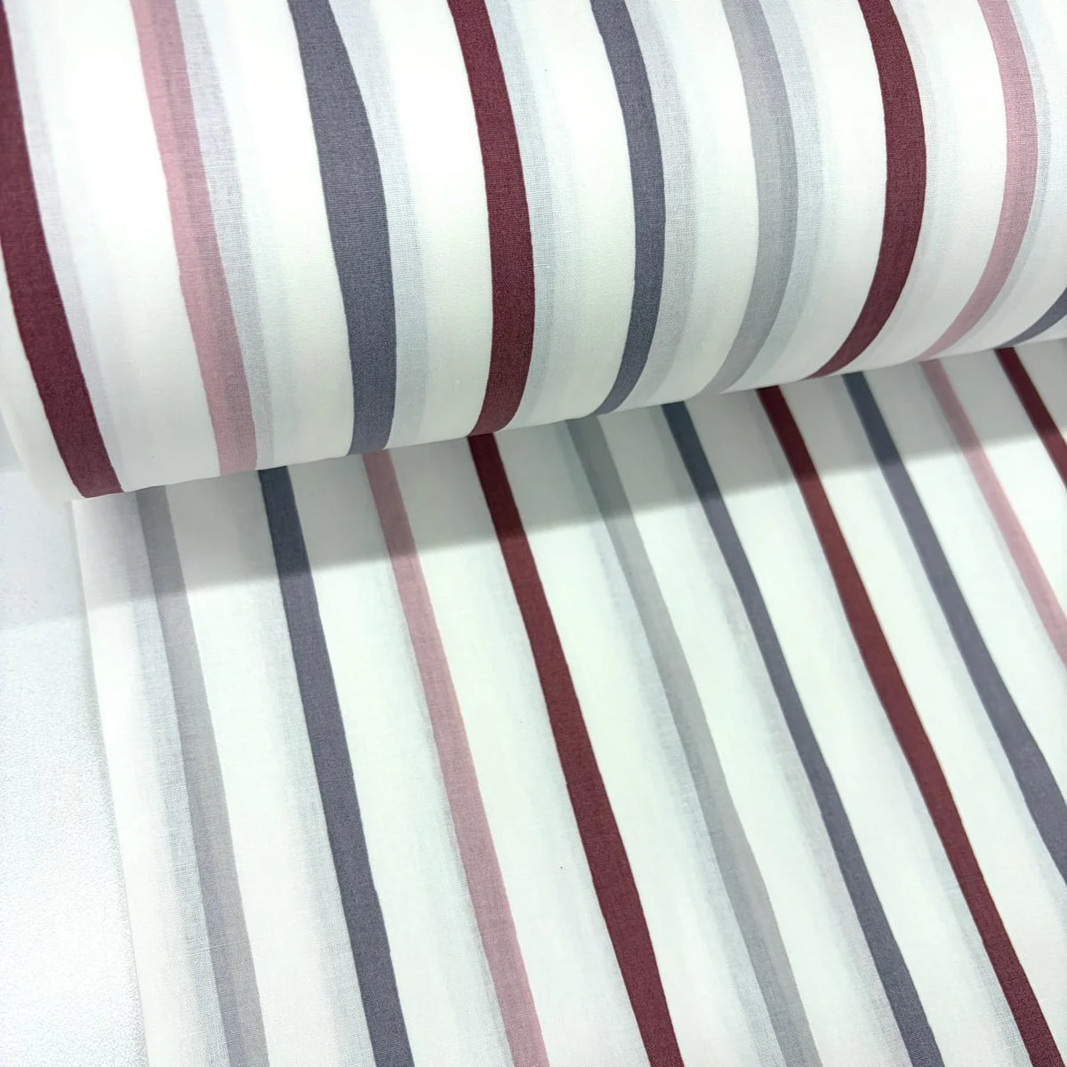 Painted stripe cotton poplin fabric with blush pink, burgundy and grey vertical stripes on a white background.