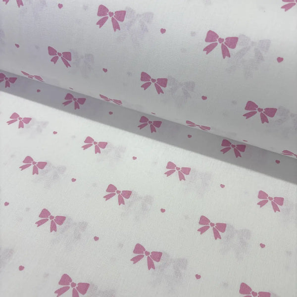 Cotton poplin fabric with pink bow pattern on a white background