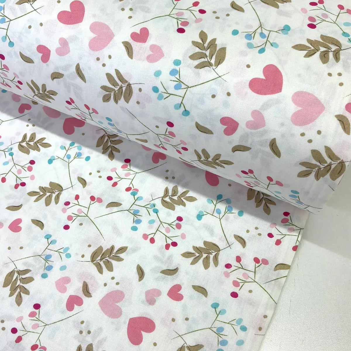 Cotton poplin fabric patterned with pink hearts and blue and brown botanical foliage on a white background.