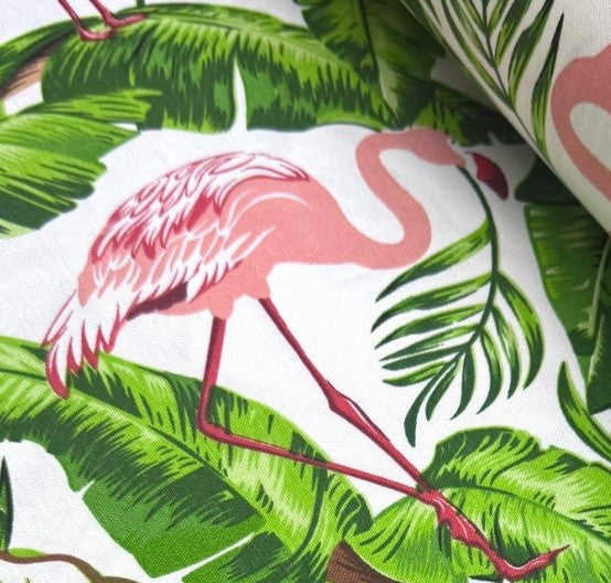 Close up of pink flamingo and green leaves printed fabric on a white background.
