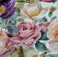 Close-up of a floral patterned fabric with pink, purple, and white flowers on a light background.