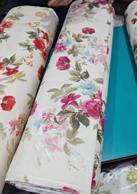Rolls of floral-patterned upholstery fabric with a blue desk underneath.