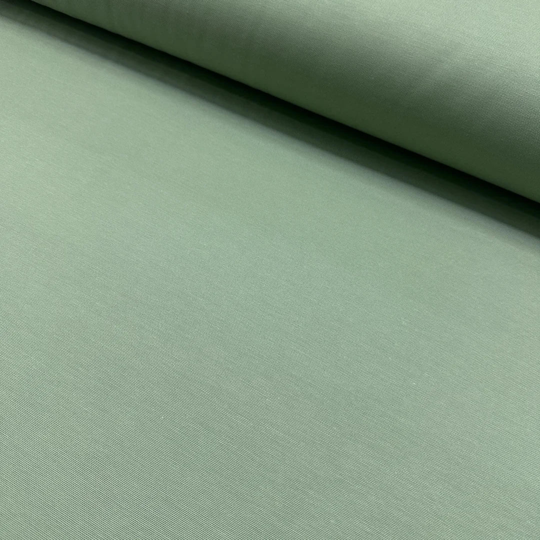 Sage green cotton canvas fabric with a plain woven texture, ideal for upholstery, curtains, cushions, bags, crafts, and soft furnishing projects.
