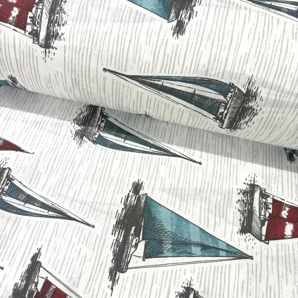 Vintage nautical fabric featuring hand-drawn sailboats with blue, teal and red sails on a textured white background.