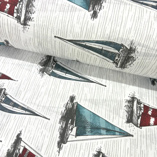Vintage nautical fabric featuring hand-drawn sailboats with blue, teal and red sails on a textured white background.