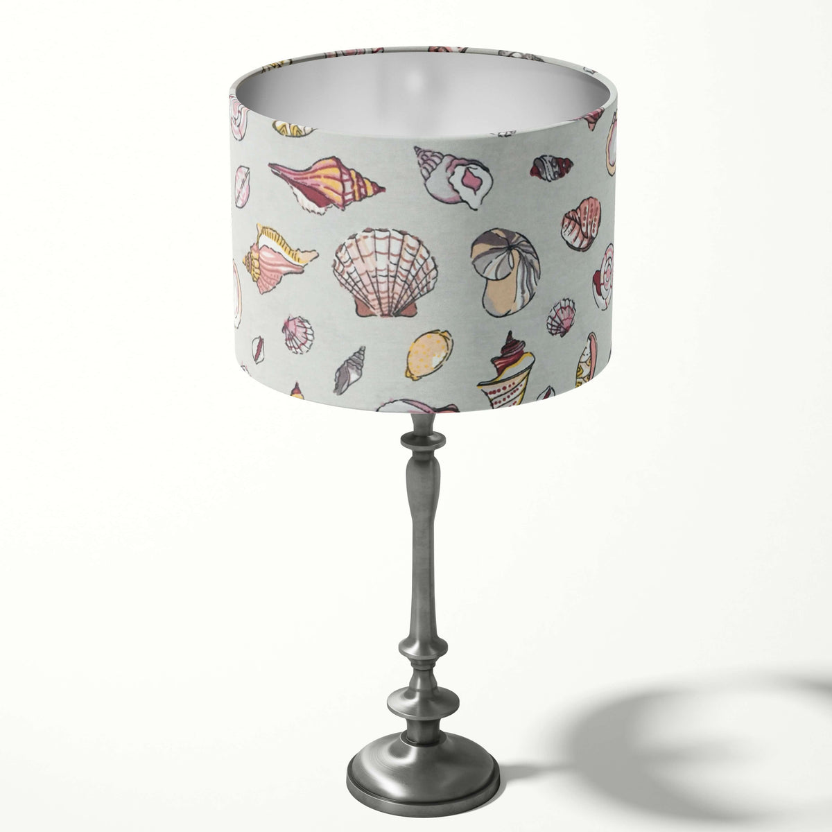 Silver grey table lampshade with pink beach shell patterns on a white background.
