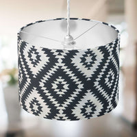 Ceiling lampshade with black and white geometric pattern hanging against a blurred indoor background.