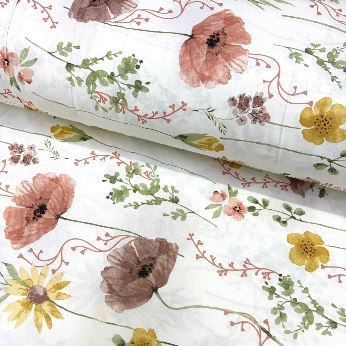A white cotton poplin fabric with a watercolour floral print featuring dusty pink poppies, yellow daisies, and green leaves.