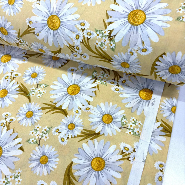 Daisy cotton poplin fabric featuring large white daisies with yellow centres on a mustard yellow background.
