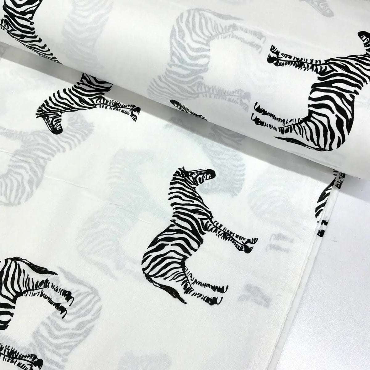 Black and white zebra print cotton fabric featuring safari zebras on a white background.
