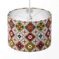 A red, green and grey geometric tile patterned lamp shade on a white background.