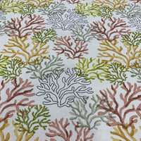 A fabric with an under the sea or ocean theme, featuring coral reef patterns in red, mustard, green on a white background.