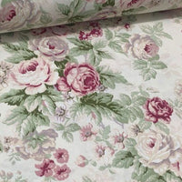 Cream floral upholstery curtain fabric patterned with light pink roses and sage green leaves.