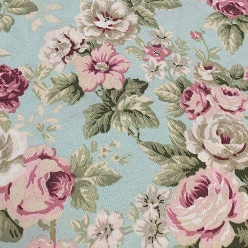Close up of floral upholstery fabric patterned with pink roses, green leaves on a mint back ground. 