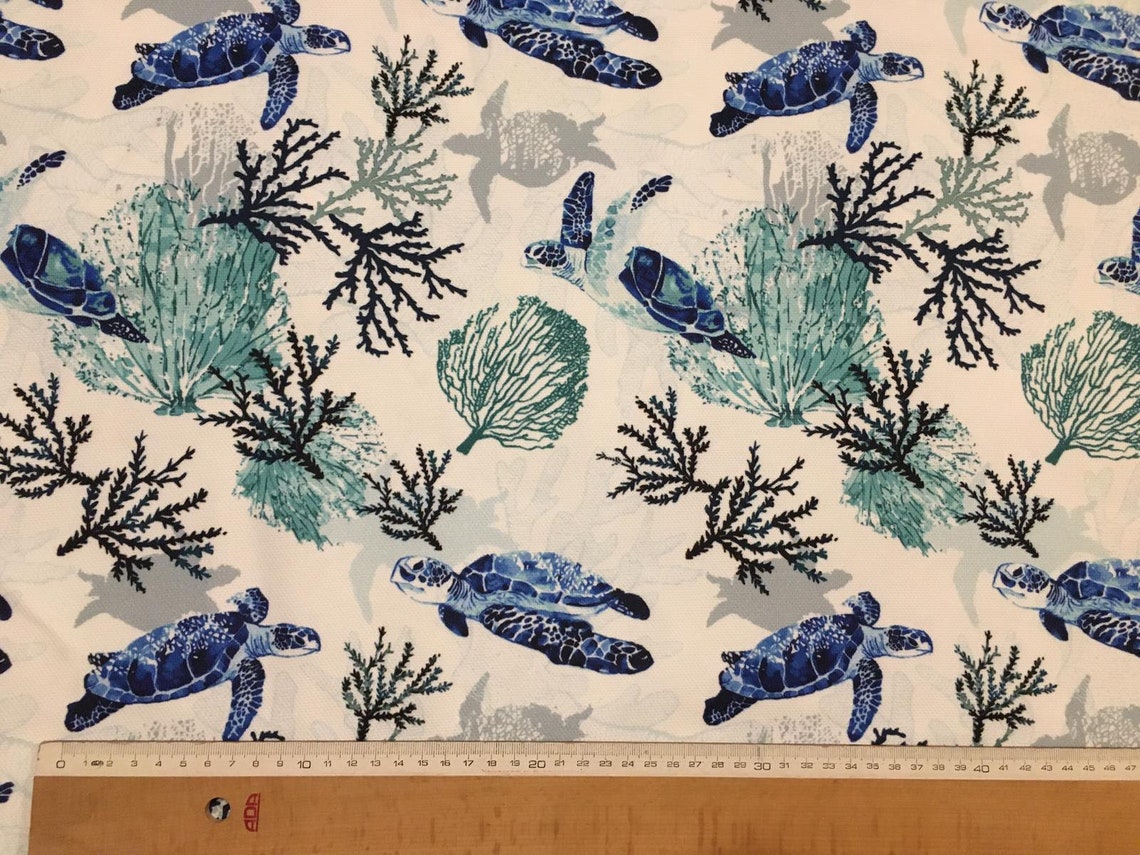 Sea turtles and seaweeds patterned ocean upholstery fabric in blue and white with a ruler showing pattern repeat.