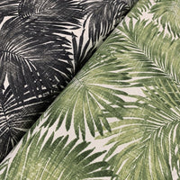 Two pieces of fabric with a tropical palm leaf pattern, one in green and the other in black, laid next to each other.