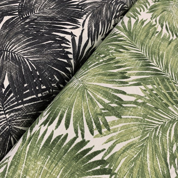 Two pieces of fabric with a tropical palm leaf pattern, one in green and the other in black, laid next to each other.